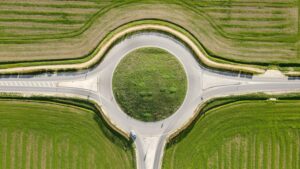 A roundabout surrounded by fields with a green centre