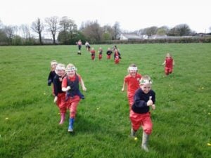 School children running through a field