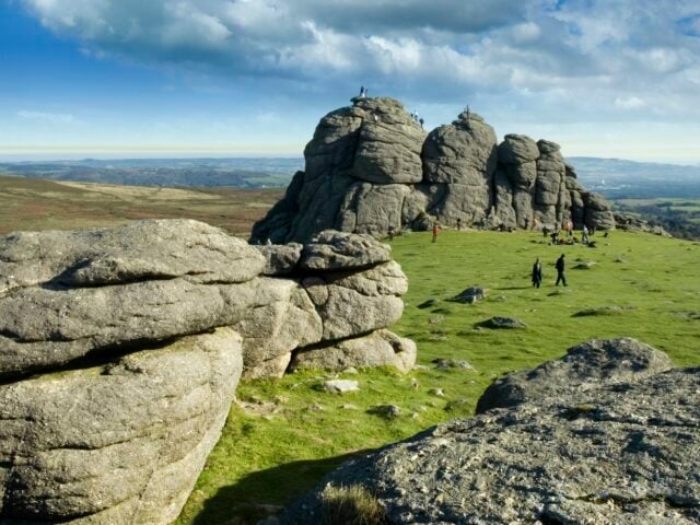 Landscape with large rock formations towering over people walking