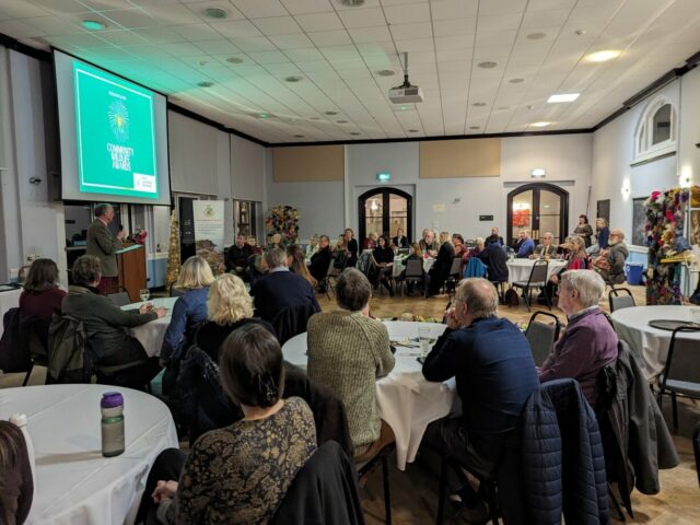 People in a large room watching a presentation