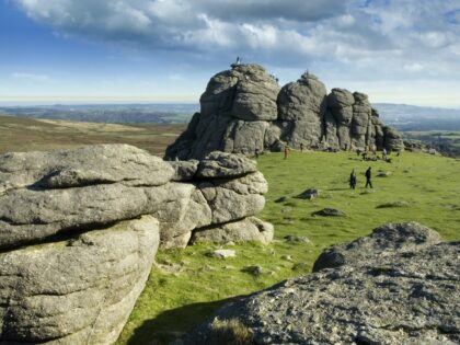 Landscape with large rock formations towering over people walking