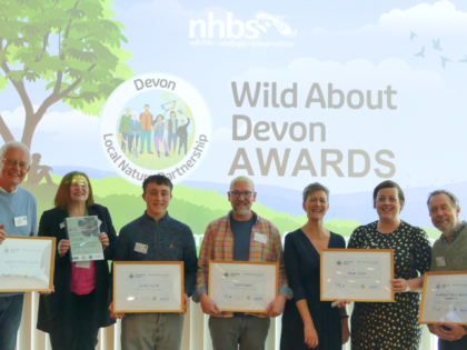 Five award winners hold certificates with Nora Corkery in front of a Wild About Devon slide