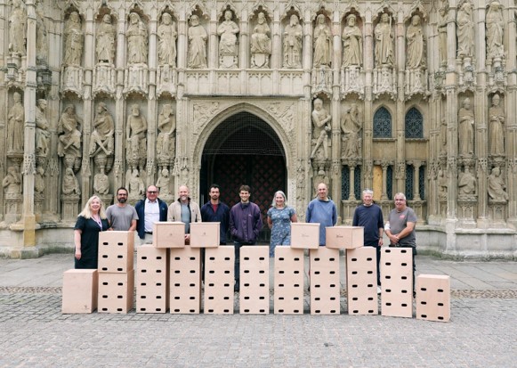 A group of people stand in front of Exeter Cathedral with swift boxes